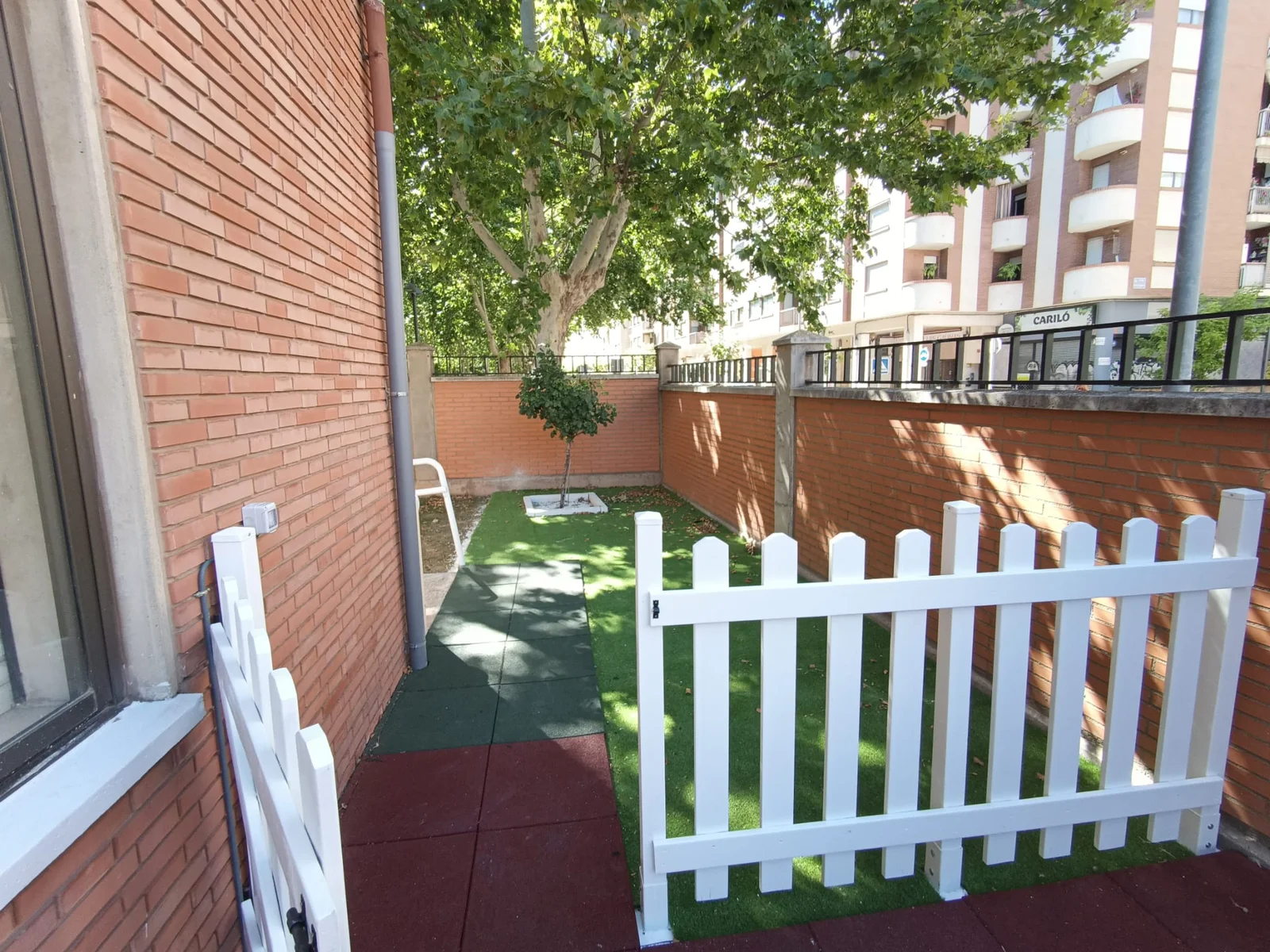 Vallado blanco y césped del patio junto a la fachada de ladrillo