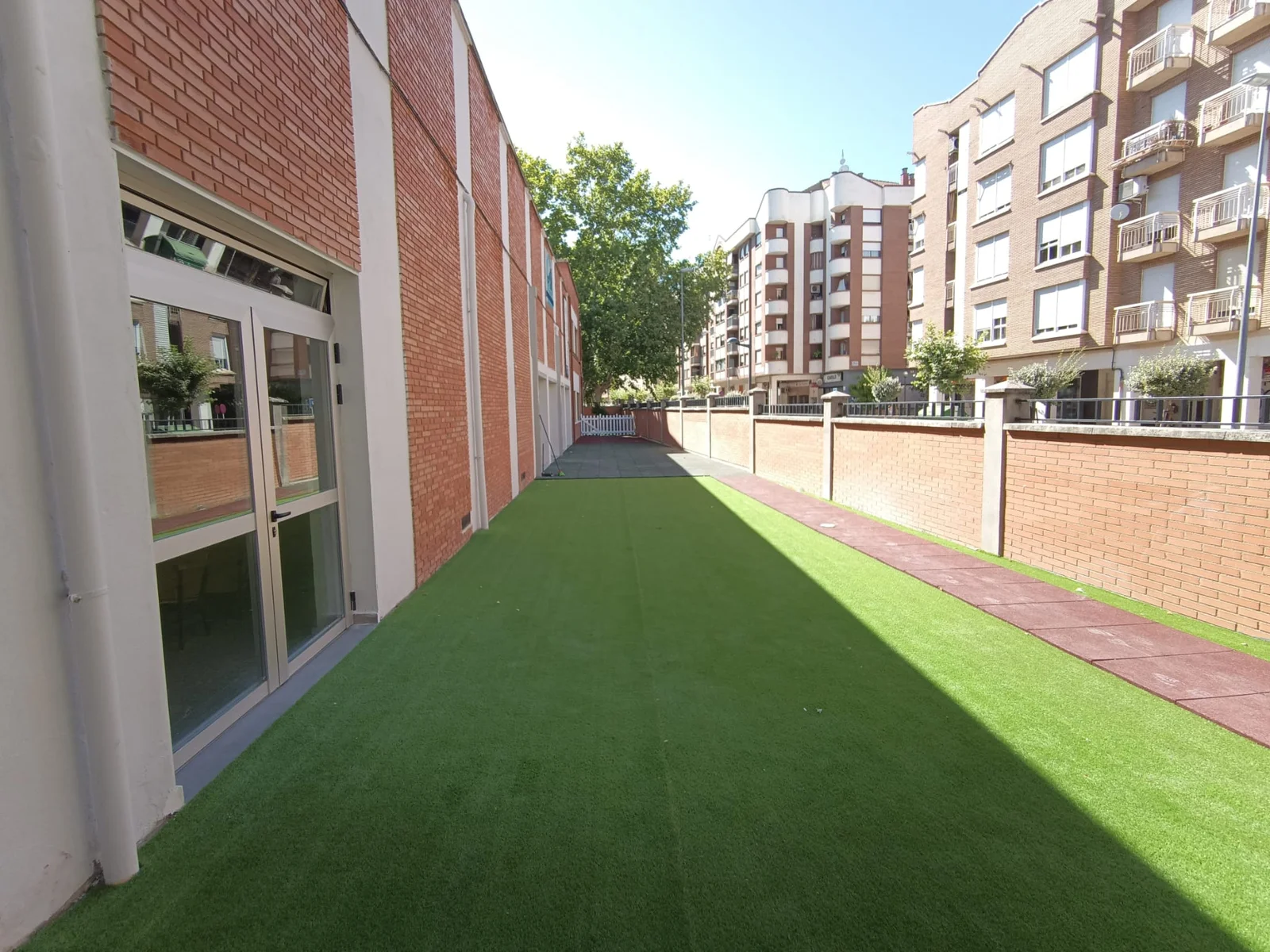 Patio lateral del colegio con césped artificial