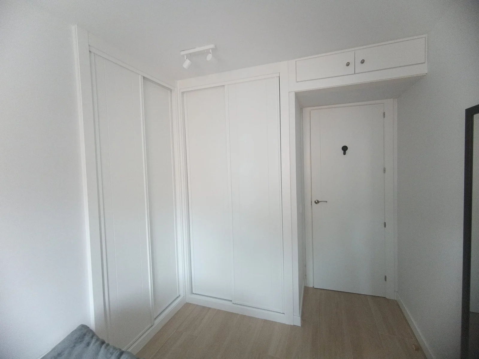 Pasillo de la vivienda con puertas lacadas y suelo de madera